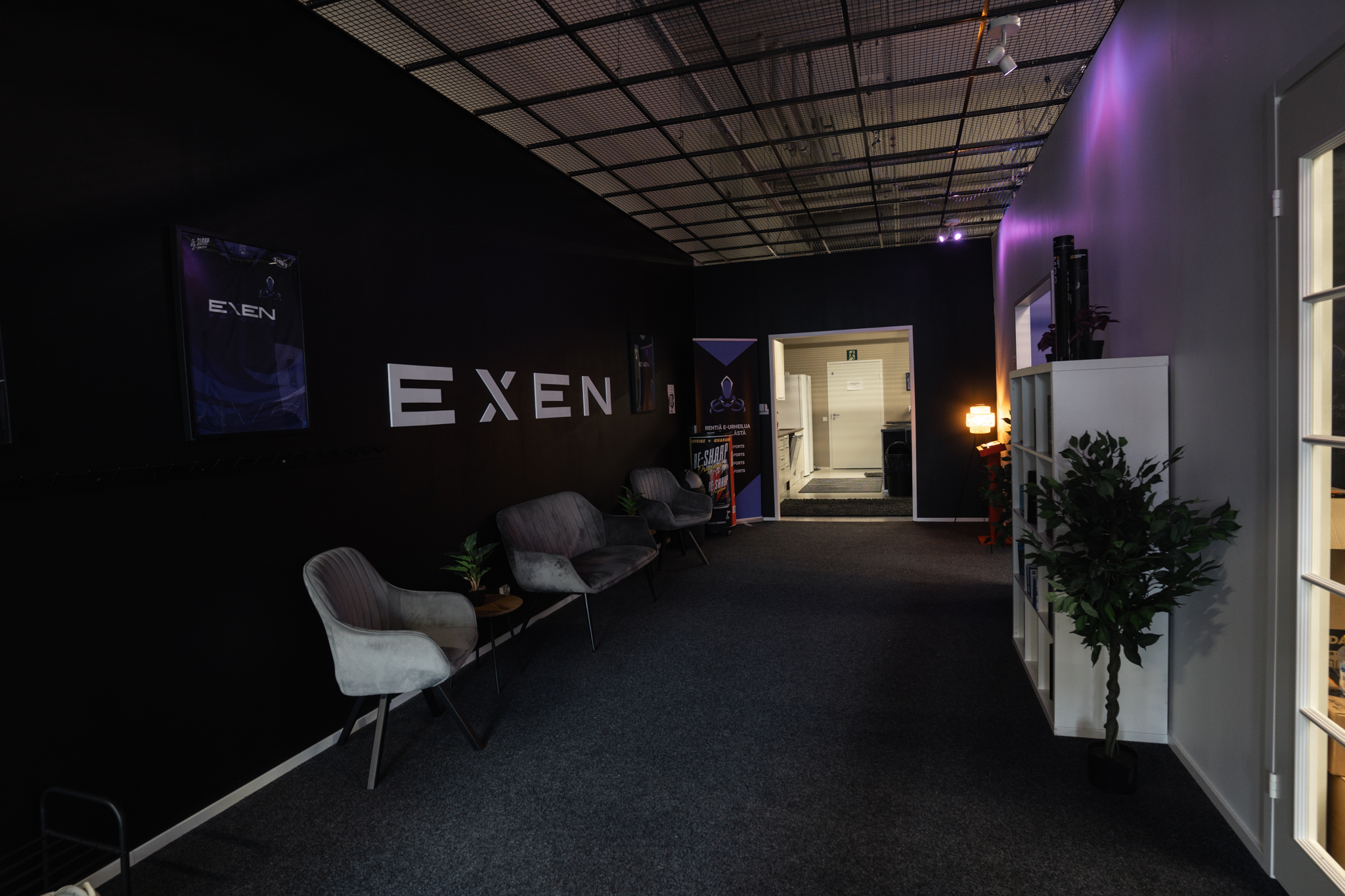 EXENin eteinen. EXEN logo valkoisella mustaa seinää vasten.