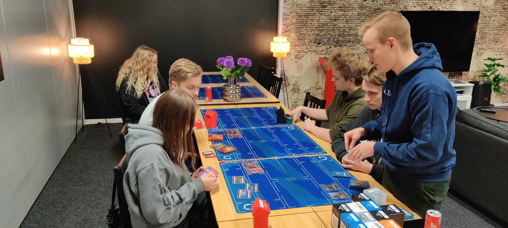 Riot Play Clubin kävijät pelaavat opastettuna Riftbound-keräilykorttipeliä.